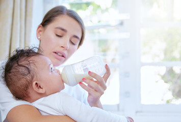 Mother, milk and feeding baby with bottle by window for nutrition, vitamin or diet at home. Mom...