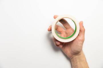 Hand holding adhesive tape on a white background. Molar tape in a man's hand, product demonstration