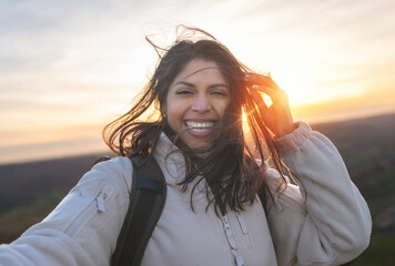 enjoying indian woman reaching destination taking selfie on mountain at sunset toned image