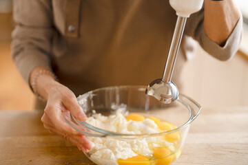 hands of woman mixing kneading dough on table in kitchen