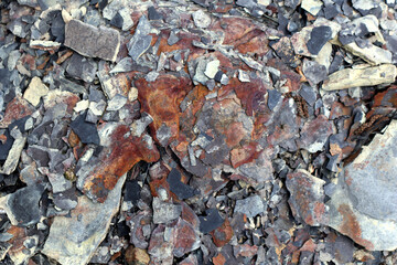 Photo of stone texture. Macro. Various shades of brown, orange, red, gray and white. Stones of different sizes. They have black cracks and crevices. Chaotic placement.