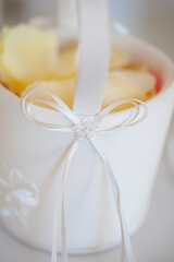 A beautiful white basket adorned with a ribbon and petals, ideal for weddings, exuding elegance and charm