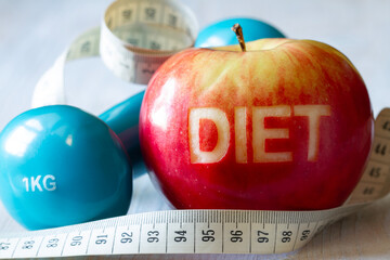 Red apple with cut-out word diet, measuring tape and dumbbell, diet and healthy lifestyle concept