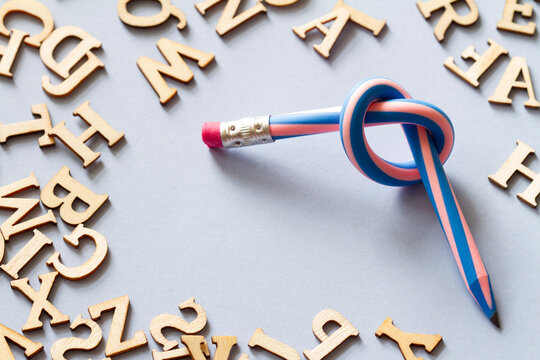 Pencil with knot and scattered letters, dyslexia concept