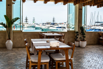 Restaurant with tables in the port overlooking the harbor with yachts on a sunny summer day, Kemer,...
