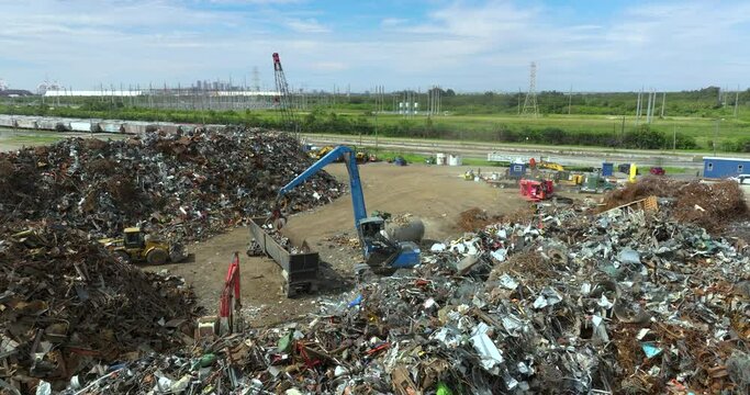 Industrial claw cranes working at metal utilization junkyard. Steel recycling plant with heap of crushed metallic waste. Transport equipment at disposal site