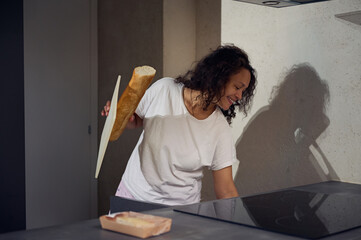 Authentic portrait of a multi ethnic young adult woman smiling broadly while holding a loaf of...