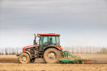 Fototapeta premium A modern tractor tilling farmland, preparing the soil for planting crops