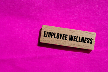 Employee wellness words written on wooden block with pink background. Conceptual employee wellness symbol.