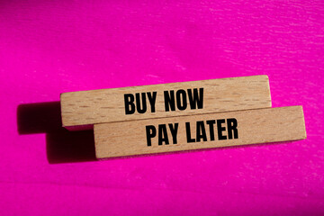 Buy now pay later words written on wooden blocks with pink background. Conceptual buy now pay later...