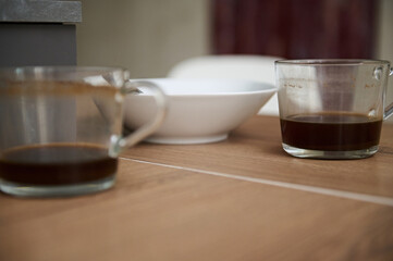 Close-up left over of breakfast in white ceramic bowl and two glass cups of unfinished coffee on the table
