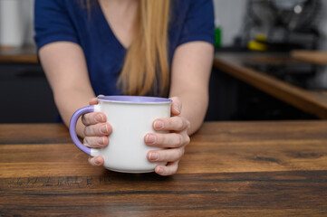 Kobieta trzyma w dłoniach duży porcelanowy kubek, pije ziółka  © Paweł Kacperek