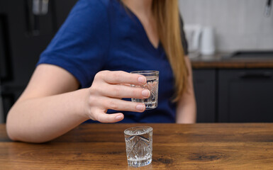 Kobieta trzydziestolatka uzależniona od alkoholu pije w domu wódkę 