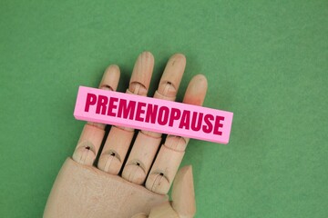 hand holding colored paper with the word premenopause. the concept of the female menstrual cycle