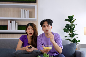 Young couple is watching television in  the living room.