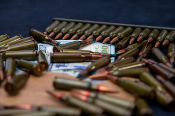 Bullets from a rifle lie on dollar bills. Selective focus.