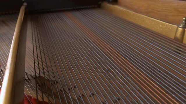 Explore a closeup of piano strings and soundboard, revealing meticulous craftsmanship in music instrument design