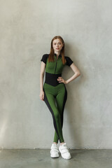 Fototapeta premium young girl in a tracksuit on a wall background. Free space for text. Wide angle horizontal wallpaper or web banner. 