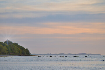 Sunset, illuminated sea. Sandy beach in the foreground. Light waves. Baltic Sea
