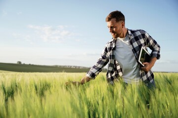 Black digital tablet in hands. Handsome man is on the agricultural field at daytime