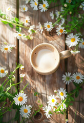 A cup of coffee with milk on an old wooden table, surrounded by white flowers and green grass in the garden