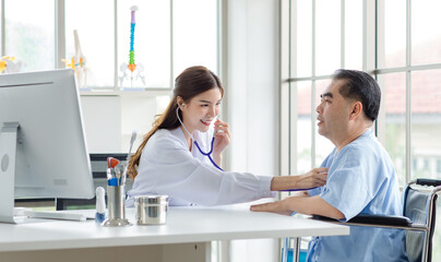 Asian young woman doctor is using a stethoscope listen to the heartbeat of elderly patient. Shot of a female doctor giving a male patient check up  in hospital, Healthcare concept.