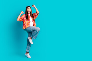 Full size photo of nice young girl raise fists empty space ad wear plaid shirt isolated on teal...