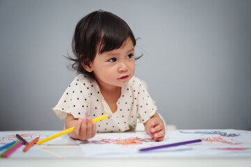 toddler baby playing and training to drawing with colored pencil on table