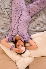 Teenage girl playfully holds sleep mask while lying on bed.