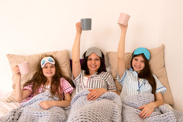 Happy family moment with mugs raised high in bed.
