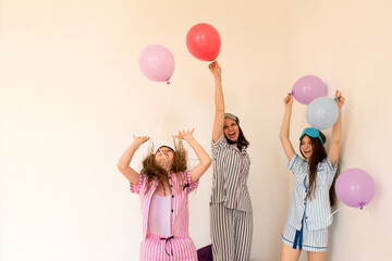 Woman and girls celebrating with balloons in pajamas at home.