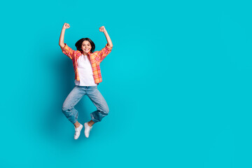 Full size photo of nice young girl jump raise fists empty space wear plaid shirt isolated on teal...