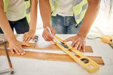 Hands, handyman and plank on table with tape for measurement, accuracy and check size for inspection. Architecture, contractor and blueprint for floor plan, equipment and renovation project in office