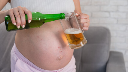 Faceless pregnant woman pouring beer into a glass. 