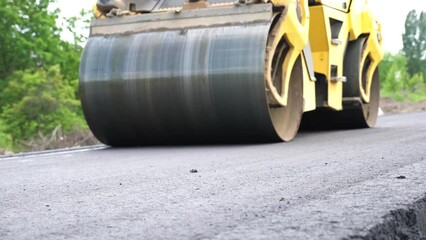 Compactor constructing highway. Steamroller slowly ride. Roadway repair by heavy machinery. Roller laying new asphalt layer. Special machinery making road. Concept of roadwork and motorway maintenance
