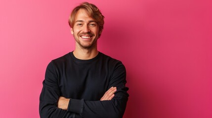 Fototapeta premium A stylish man stands with arms crossed in front of a vibrant pink background