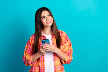 Photo of nice young girl hold phone look empty space wear plaid shirt isolated on teal color...