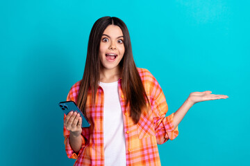 Photo of nice young girl hold empty space phone wear plaid shirt isolated on teal color background