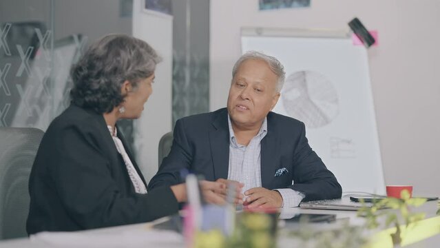 Indian Asian old gen x aged angry sad man woman sitting chair do team work talk argue scold yell fail client deal job office elder upset boss male tired older female fight money loss bad crisis claim