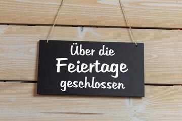 Symbolbild Betriebsferien: Schild an einer Holztafel mit der Aufschrift ÜBER DIE FEIERTAGE...