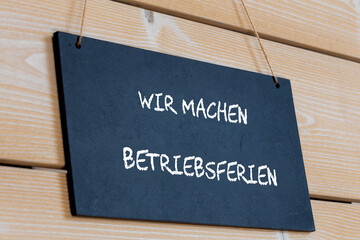 Symbolbild Betriebsferien: Schild an einer Holztafel mit der Aufschrift WIR MACHEN BETRIEBSFERIEN