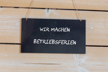 Symbolbild Betriebsferien: Schild an einer Holztafel mit der Aufschrift WIR MACHEN BETRIEBSFERIEN