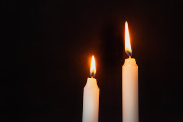 Two lit candles on a dark background