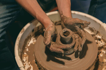 Hands Shaping Clay Pot on Pottery Wheel in Workshop