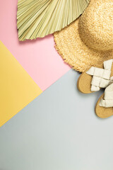 Top view of straw hat, slippers and dried palm leaf on colorful background. Summer fashion,...