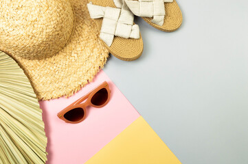 Top view of straw hat, slippers, sunglass and dried palm leaf on colorful background. Summer...