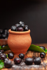 A mud pot filled with 'Indian blackberry' or Jamun (Syzygium cumini) fresh fruits, sprinkled with salt. 