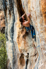 strong rock climber is climbing an overhanging rock.