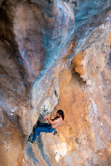 male climber.  strong muscular male rock climber climbs a vertical rock and makes great efforts to...