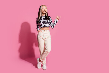 Full length photo of cheerful pretty lady dressed cow skin shirt pointing empty space isolated pink color background